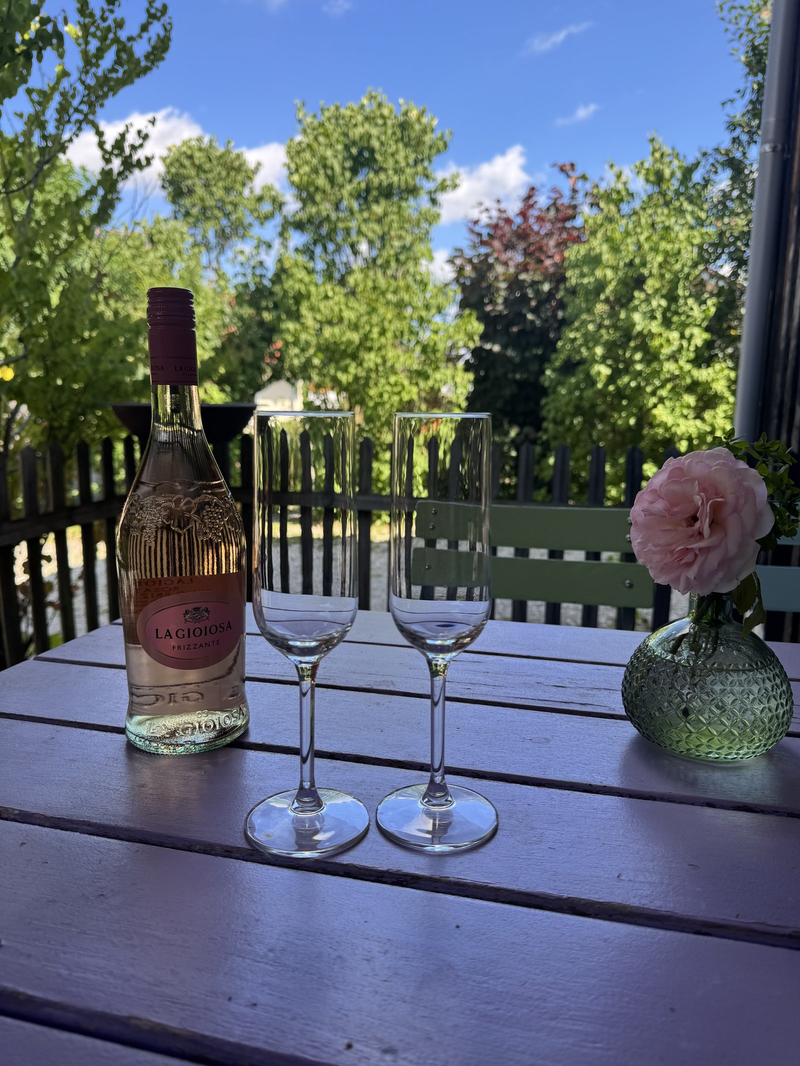 Tisch mit Sektflasche, zwei Gläsern und Blumen